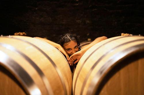 a woman peeking out from between two wine barrels at Greet Hotel Colmar in Colmar