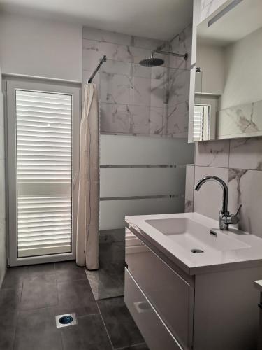 a white bathroom with a sink and a mirror at Apartments Bjanka in Žuljana