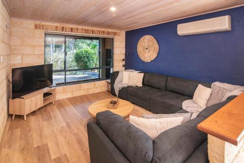 a living room with a couch and a tv at Sea Glass Beach House Gnarabup in Gnarabup