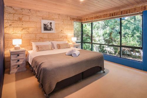 a bedroom with a large bed and a large window at Sea Glass Beach House Gnarabup in Gnarabup