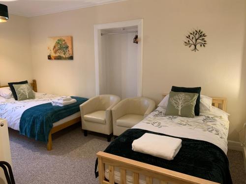 a room with two beds and a chair in it at The Village Inn in Kirtlebridge