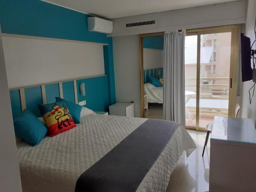 a bedroom with a large bed with blue walls at Hotel Clibomar Jamaica in Gandía