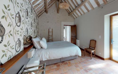 a bedroom with a large bed and a chair at Le Petit Pavillon in Cheverny