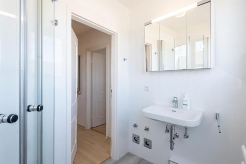 un bagno bianco con lavandino e specchio di Haus Nordseegruss, App 4 a Wenningstedt