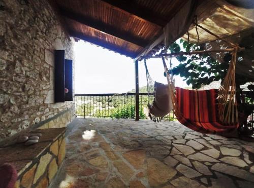 a porch with a hammock hanging from a building at Panorea's Stone House in Sidhirókastron