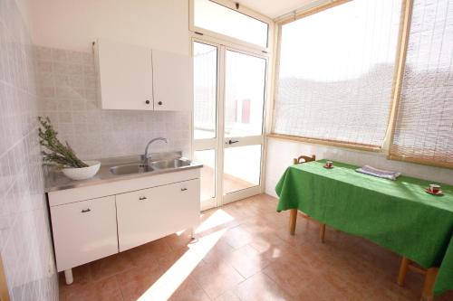 een keuken met een wastafel en een tafel met een groene tafelkleed bij Casa Montegrappa by RENTHOUSESALENTO in San Foca