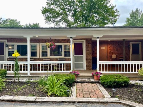 a small house with a porch and flowers on it at Kennebunkport Motor Lodge in Kennebunkport