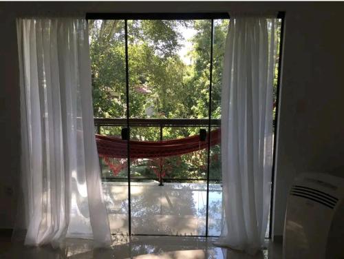 ein Fenster mit weißen Vorhängen und Blick auf einen Hof in der Unterkunft Ohana suíte Abraão - Ilha Grande in Abraão