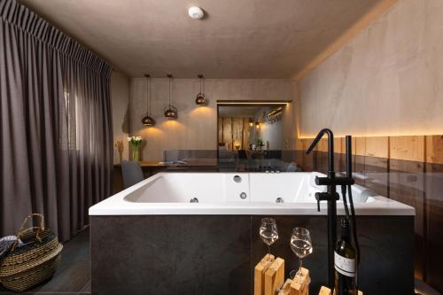 a bathroom with a tub with two wine glasses at Tsikeli Boutique Hotel Meteora - Adults Friendly in Kalabaka