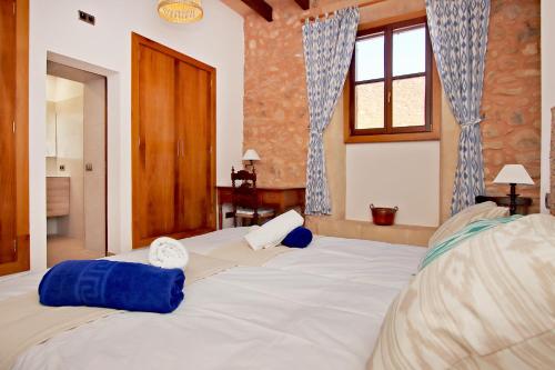 a large white bed with blue pillows on it at Villa Son Pons by Slow Villas in Llucmajor