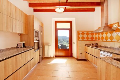 a large kitchen with wooden cabinets and a window at Villa Son Pons by Slow Villas in Llucmajor