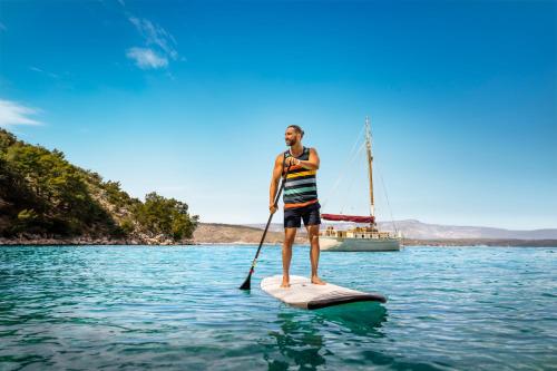 a man standing on a paddle board in the water at PLACES Dalmacija by Valamar in Makarska