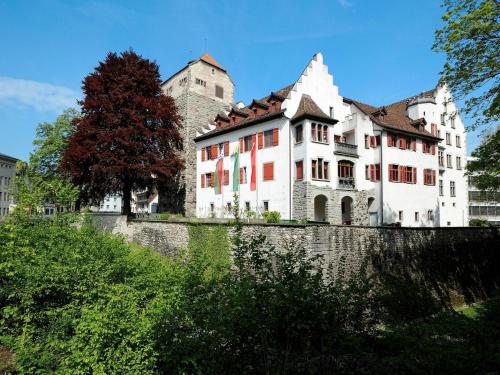 a large white building with a castle in the background at Hotel Müllers Self-Check-In in Arbon