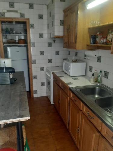une petite cuisine avec un évier et un micro-ondes dans l'établissement Appart 50m carré maxi 6 personnes vue panoramique montagne, à La Llagonne