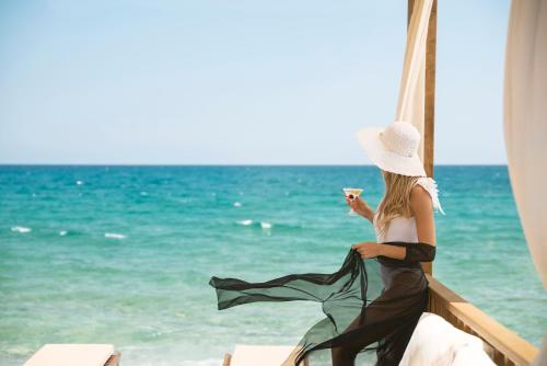 a woman sitting on the beach with a drink at Akka Antedon Hotel - Premium Ultra All Inclusive in Beldibi
