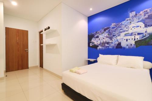 a bedroom with a white bed and a blue wall at Locus Rooms in Bandung