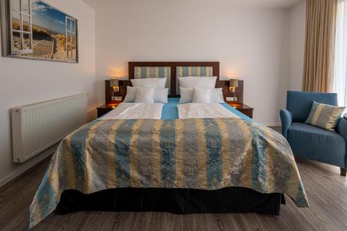 a hotel room with a bed and a blue chair at Hotel Nordstern in Neuharlingersiel