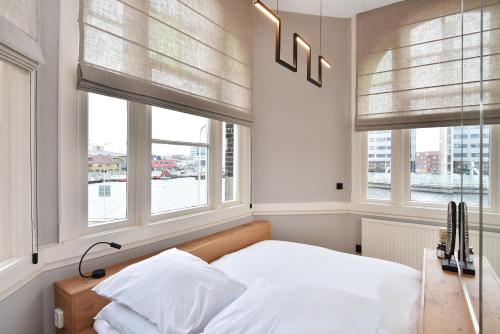 a bedroom with windows and a bed with white sheets at Boutique Hotel Havenkantoor in The Hague