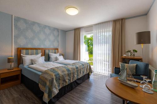 ein Hotelzimmer mit einem Bett, einem Schreibtisch und einem Fenster in der Unterkunft Hotel Nordstern in Neuharlingersiel