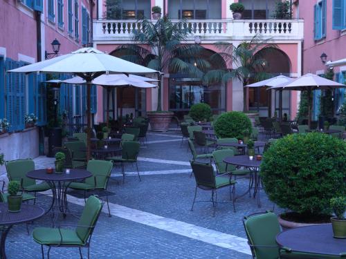 an empty patio with tables and chairs and umbrellas at Rocco Forte Hotel De Russie in Rome