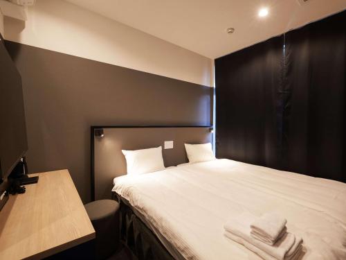 a bedroom with a bed with two towels on it at CABIN&HOTEL CONSTANT NAHA in Naha