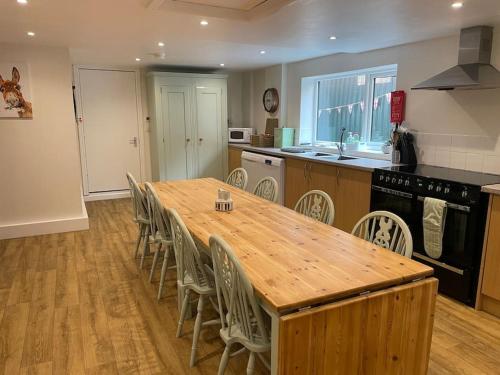 een keuken met een grote houten tafel en stoelen bij The Old Dairy Accommodation in Tillingham