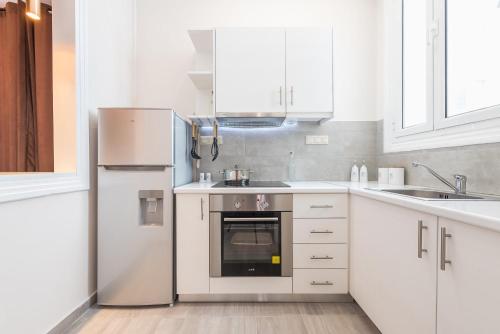 a kitchen with white cabinets and a refrigerator at Athens Lights in Athens