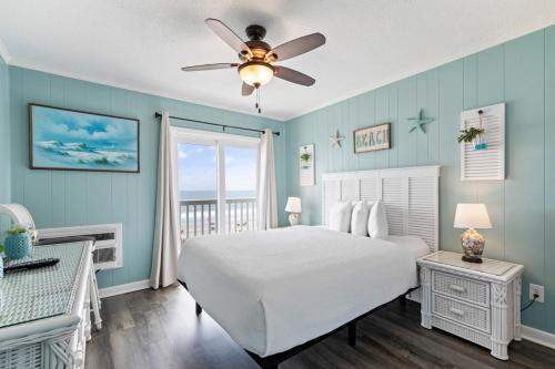 a bedroom with a white bed and a ceiling fan at Bright and Sunny Condo with Stunning Oceanfront in Myrtle Beach