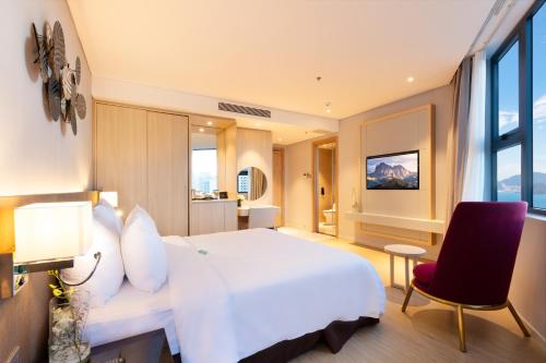 a bedroom with a white bed and a red chair at DQua Hotel in Nha Trang