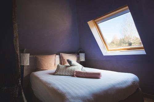 a bedroom with a large bed with a window at Locations - Domaine Le Coq Enchanté in Cambremer