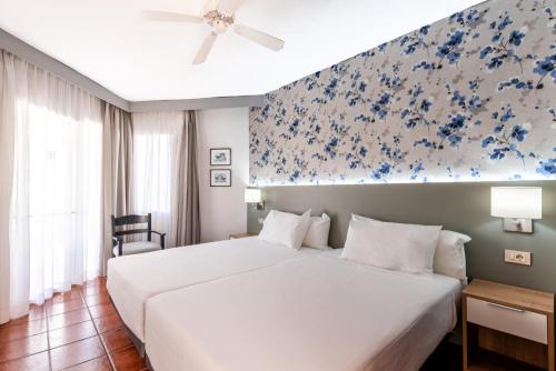 ein Schlafzimmer mit einem großen weißen Bett mit blauen Blumen an der Wand in der Unterkunft HG Tenerife Sur in Los Cristianos