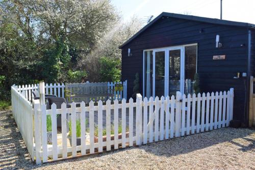a white picket fence in front of a blue shed at The Goat House in Purleigh