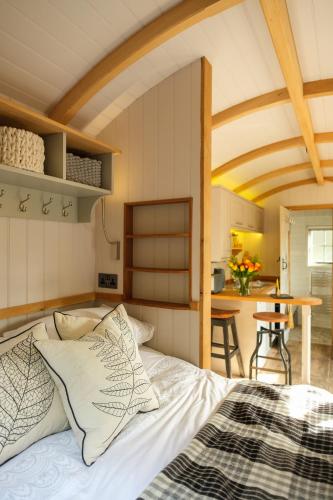 a bedroom with a bed and a kitchen with a table at Piano Forte - delightful rural shepherd hut retreat & hot tub available in Rushford
