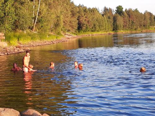 a group of people swimming in a river at Kalix Riverside inn, Farm timbering in Kalix