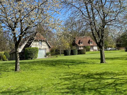 a group of trees in a field with a house at Locations - Domaine Le Coq Enchanté in Cambremer