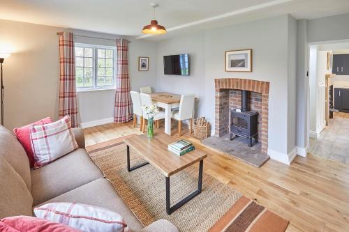 sala de estar con sofá y chimenea en Host & Stay - Gardeners Cottage, en Brafferton