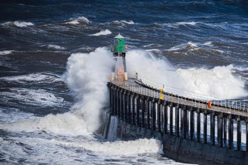 a lighthouse in the middle of the ocean with waves at La Rosa Hotel in Whitby