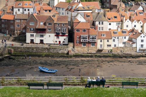 a group of people sitting on a bench near the water at La Rosa Hotel in Whitby