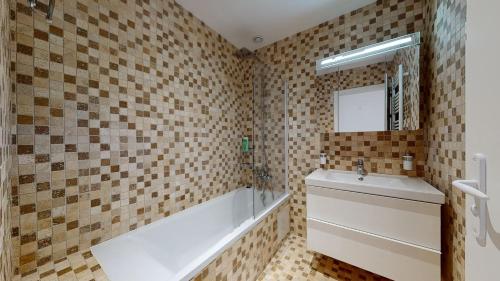 a bathroom with a tub and a sink and a mirror at VILLA MAGNYSOLAR Proche Disneyland Paris in Magny-le-Hongre