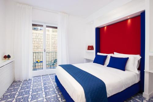 Schlafzimmer mit einem großen Bett mit einem roten Kopfteil in der Unterkunft Blue Splendor Sorrento Apartment in Sorrent