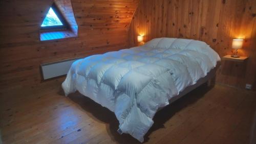 a bedroom with a bed with a white comforter and a window at Fermette typique auvergnate dans son écrin d'eau et de verdure in Saint-Donat