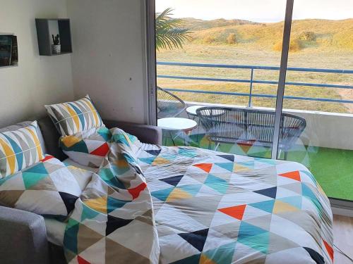- un lit avec une couette colorée en face d'une fenêtre dans l'établissement Appartement avec Vue sur Mer à Saint-Jean-de-Monts, 30 m², Balcon, à Saint-Jean-de-Monts