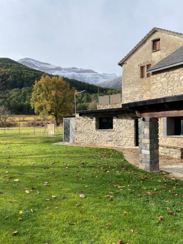 Casa Rural Aracanciás في Borrastre: بيت حجري في حقل فيه جبال في الخلف