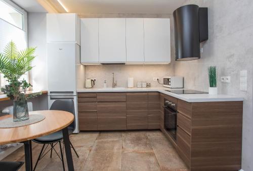 a kitchen with white cabinets and a wooden table at Urban Jungle apartment in the heart of the city in Białystok