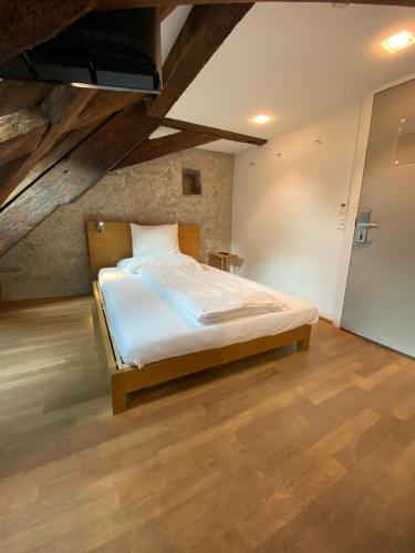 a bedroom with a bed in a room with wooden floors at Hotel Lestelle - self check-in in Luzern