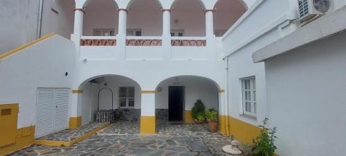 Edificio blanco con arcos y balcón en Guesthouse da Vila en Mourão