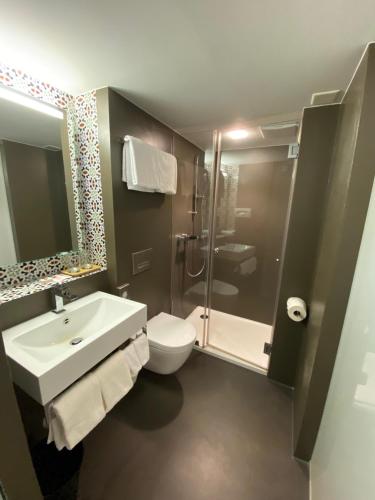 a bathroom with a sink and a toilet and a shower at Hotel Lestelle - self check-in in Luzern