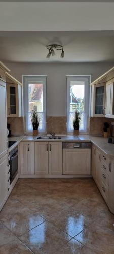 una grande cucina con mobili bianchi e finestre di Balaton Villa a Gyenesdiás