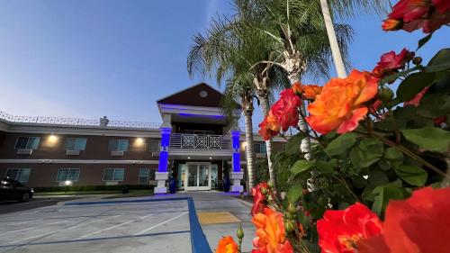 a building with palm trees and flowers in front of it at Best Western Americana in Dinuba