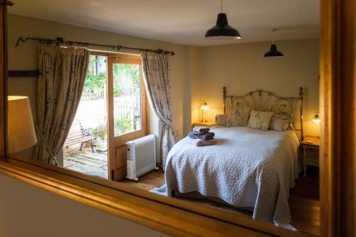 een spiegel die een slaapkamer met een bed en een raam weerspiegelt bij Quavers Rest - quintessential little home & hot tub available ! in Rushford